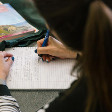 Student writing in notebook.