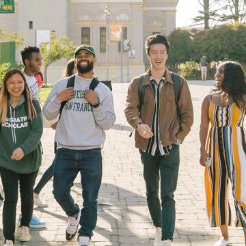 Group of students walk across Gleeson Plaza while talking.