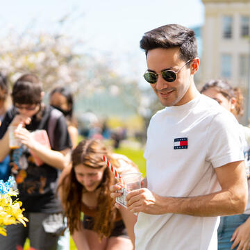 Students examine information on tables at an event on the lawn.