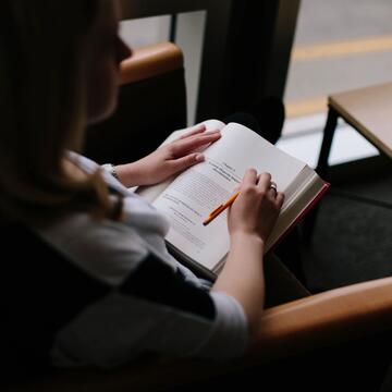 Student reads book while sitting in chair