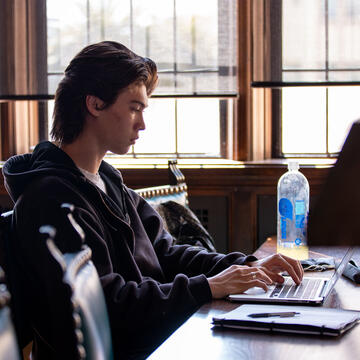 Student studies at a table in the Lone Mountain reading room.