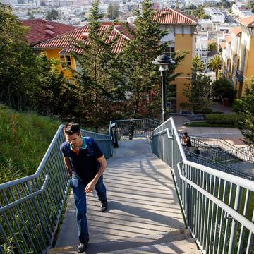 Student walking up stairs with view of Loyola Village in the background
