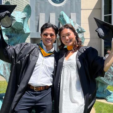 Two graduates wave their hats and pose for picture.