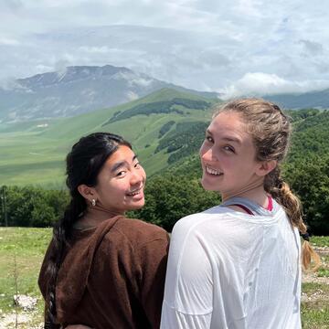 Two students sit on a hill looking over a valley