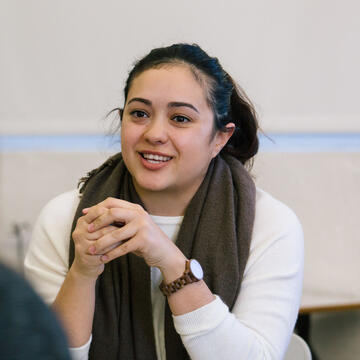 Student speaks in classroom to a colleague.
