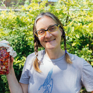 Novella Carpenter smiling and holding a jar outside