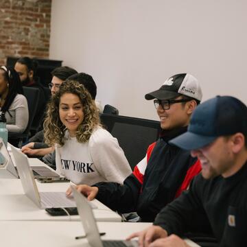 Students sitting at a table with their laptops.