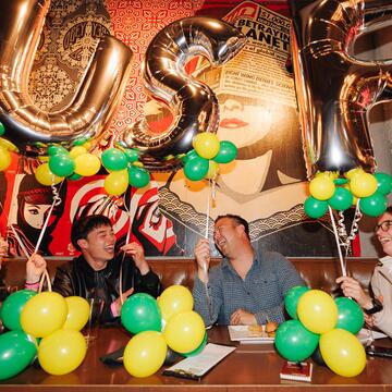 Alumni laughing and holding USF balloons