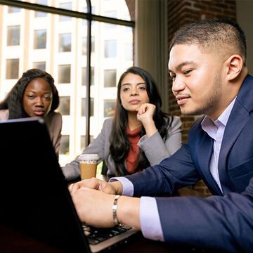 Three USF students sitting around a laptop screen