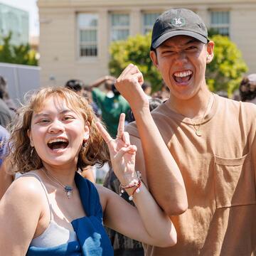 Two students holding their hands up and smiling