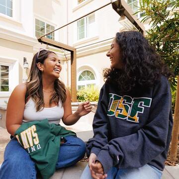 Two students sitting and talking outside