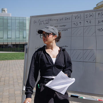 student stands outside in front of whiteboard