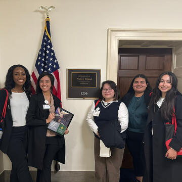 students stand in front of nancy pelosi sign