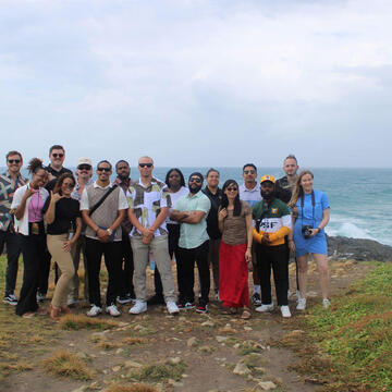 group of students pose on mountain overlooking ocean