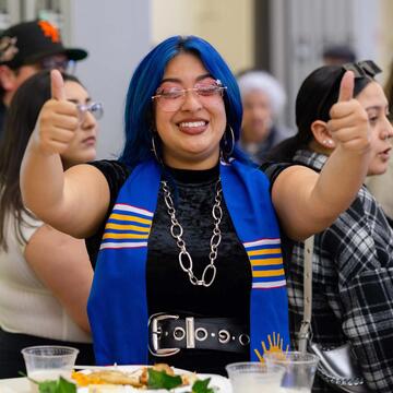 a student giving two thumbs up at a party