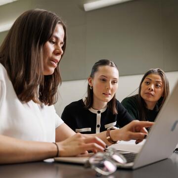 Three students looking at a laptop