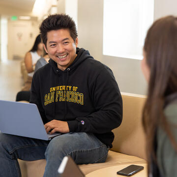 students sits on couch with laptop