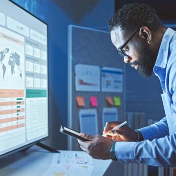 a man in front of a large computer screen making calculations