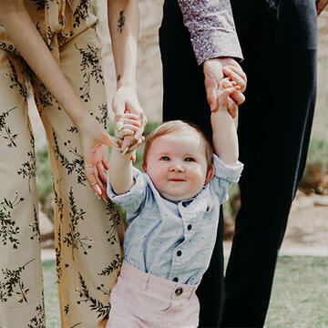 Baby holding parents' hands while taking a few steps