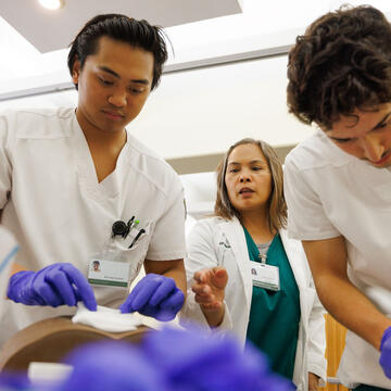 Nursing students work with an instructor in the skills lab