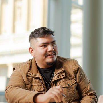 Graduate student wearing brown jacket chatting