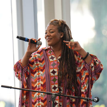 Woman in colorful dress holding microphone and singing