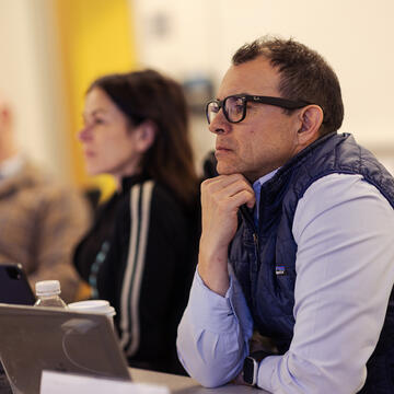 Adult wearing glasses and vest focused in class
