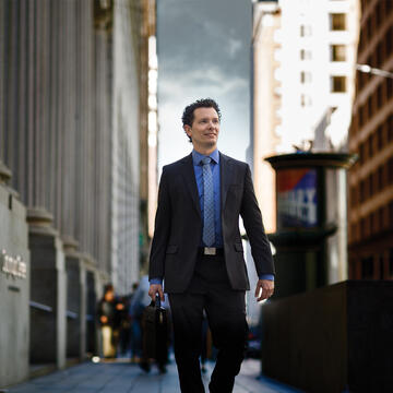 Business person walking down city street in suit and holding briefcase