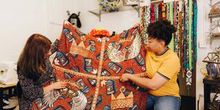 Two people holding a knit blanket