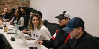 Students sitting at a table with their laptops.