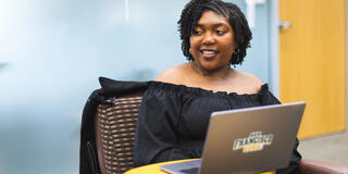 USF student smiling, sitting in front of laptop