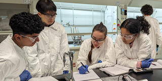 students in lab coats conduct experiments