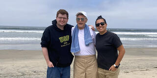 Three people smiling at the beach.