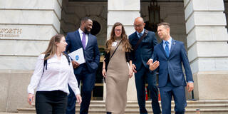 Group of professionals walking down government building steps.