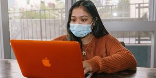 student wearing a mask and working on her laptop