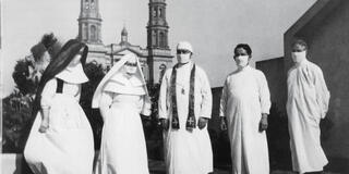 Priests and nuns wearing masks stand in front of St Ignatius Church.