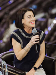 Sara Gotfredson smiling and speaking into a microphone in a stadium