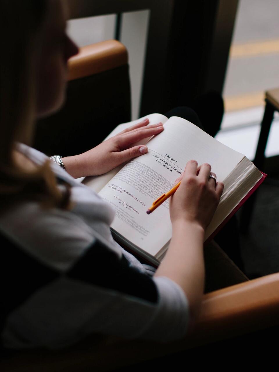 Student reads book while sitting in chair