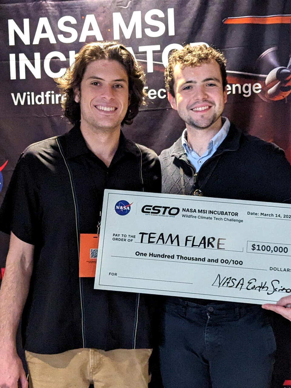 Two students hold a check for Team Flare at NASA MSI